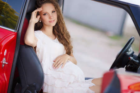 Pregnant Woman Driving a Car. pregnant woman in driving seat of the car. portrait of young beautiful pregnant woman outdoors. smiling pregnant woman sitting in carの写真素材