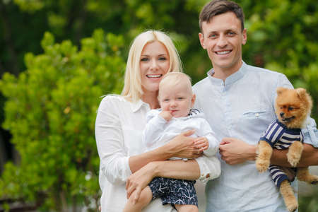 Cheerful family, mom-beautiful blonde, father-brunette with short hair and their little son, spend...