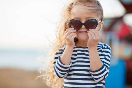 happy little girl at the seaside in the summer.Adorable little girl at beach during summer vacation. Happy baby with sunglasses by the seaの写真素材