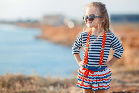 happy little girl at the seaside in the summer.Adorable little girl at beach during summer vacation. Happy baby with sunglasses by the seaの写真素材