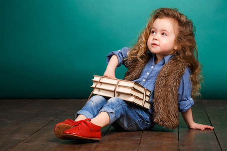 Little girl with books. Child studying. Schoolchild. Schoolgirl. studio portrait. school preparation. baby holding bunch of books. education. pupil.の写真素材