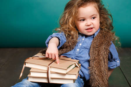 Little girl with books. Child studying. Schoolchild. Schoolgirl. studio portrait. school preparation. baby holding bunch of books. education. pupil.の写真素材