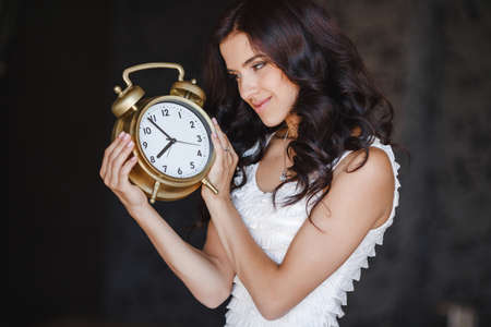 young woman holding a clock. time management concept. Young caucasian woman with alarm clock in her hands. picture of woman holding clockの写真素材