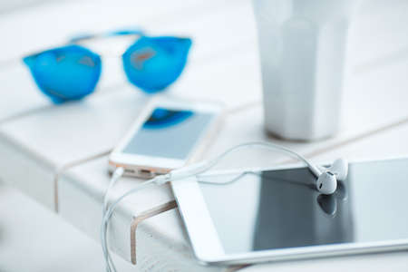 Digital tablet computer with cup of coffee on old wooden table in white cafe. Simple workspace or coffee break with web surfing. bue sunglassesの写真素材