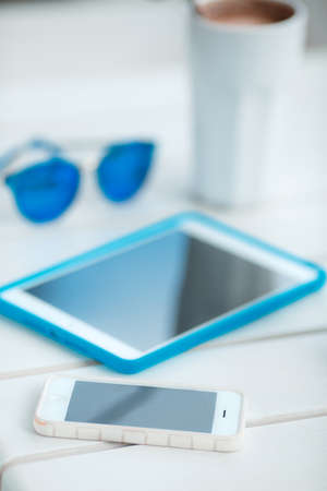 Digital tablet computer with cup of coffee on old wooden table in white cafe. Simple workspace or coffee break with web surfing. bue sunglassesの写真素材