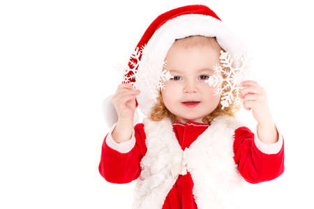 Beautiful girl dressed as Santa Claus.Cute little girl with blond curly hair and brown eyes, a nice smile, dressed as Santa Claus with a big red cap on his head, Studio portrait on white background.の写真素材