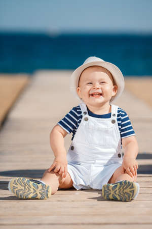 Portrait of the happy child in a hat on the seashore, Funny smiling child in a straw hat, a white...