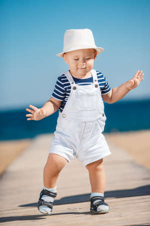 Portrait of the happy child in a hat on the seashore, Funny smiling child in a straw hat, a white...