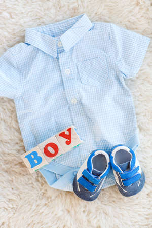 Baby clothes for newborn. In pastel colors.Children's shirt in blue white checked baby sneakers and...