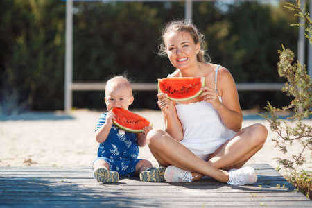 A young mother, brunette with gray eyes and curly hair, with his young son dressed in a striped...