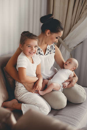 Family portrait of mother with two children, an older daughter and a newborn son at home in bedroom...
