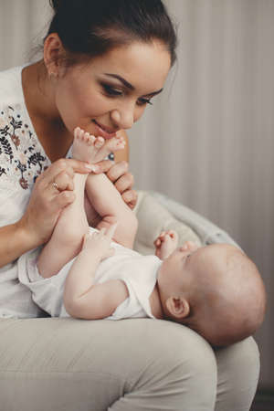 A young mother, brunette, hair pulled back, white sleeveless blouse, spending time together with...