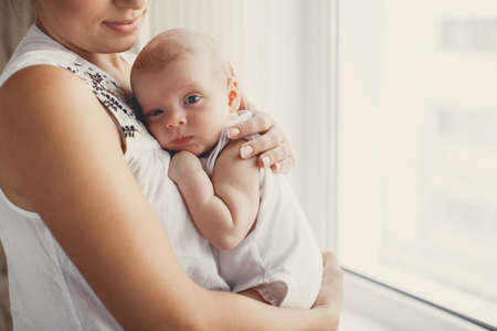 A young mother, brunette, hair pulled back, white sleeveless blouse, spending time together with...