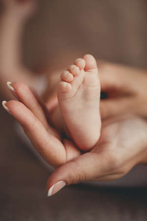 Happy young family, a mother holding foot her firstborn.A caring mother, gently holding on his palm...
