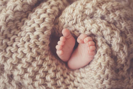 Little feet a newborn baby in a beige blanket.Little feet of a sleeping newborn baby, with tiny...