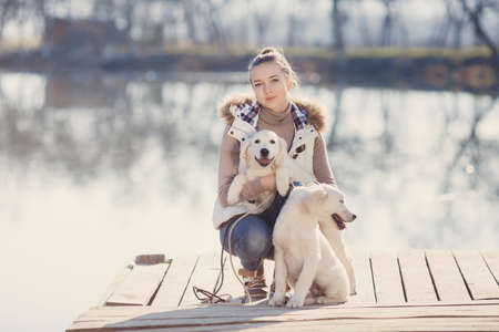 Beautiful girl with pets near the lake.Girl, brunette with gray eyes, hair pulled back, dressed in a...
