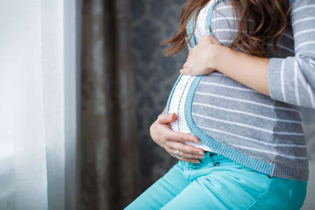 Pregnant woman touching hands big belly.Beautiful young pregnant woman, brunette with long thick...
