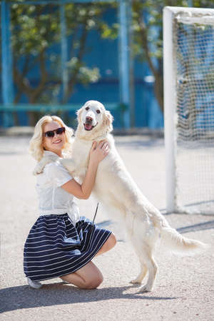 Young beautiful woman the blonde with curly hair in dark sun glasses, dressed in a white blouse and...