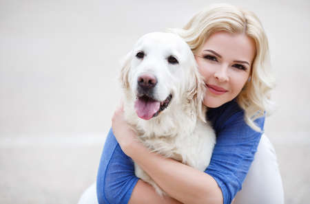 Young beautiful woman with curly blonde hair and brown eyes wearing a blue shirt and white jeans,...