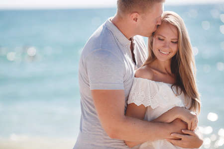 Young loving happy couple, a blond man and woman spend time together on the beach on the shore of...