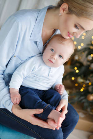 Slim young mother, a woman with blond hair gathered at the nape, spends time with young son near...
