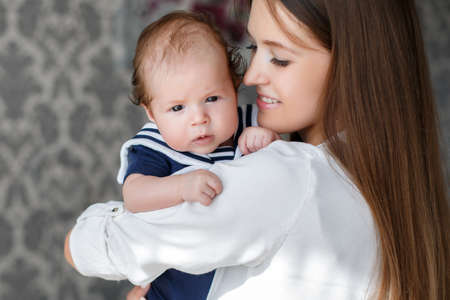 Portrait of mother and child, beautiful mother, brunette with long straight hair, dressed in a white...