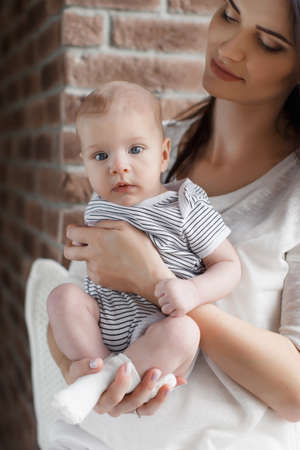 Newborn baby boy with blond short hair, spends time with his mother, a woman, a brunette with long...