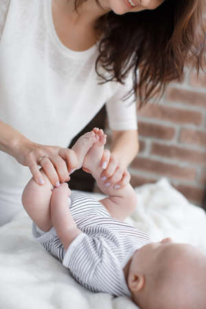 A young mother, brunette with long thick hair, is dressed in white pants and a white t-shirt, doing...