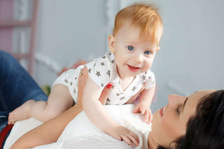 Funny kid with red hair and blue eyes, dressed in a white t-shirt with grey stars and plays on the...