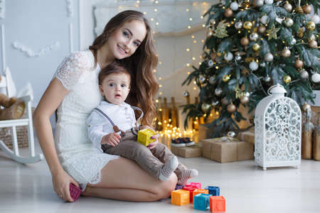 Happy family mother and little son near christmas tree on Christmas Eve. A woman playing with her son in anticipation of the New Yearの写真素材