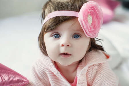 Close-up of a six, seven months old baby girl with blue eyes. Newborn child, little adorable smiling and attentive girl looking surprised at the camera. Family, new life, childhood concept. Christmas Eveの写真素材