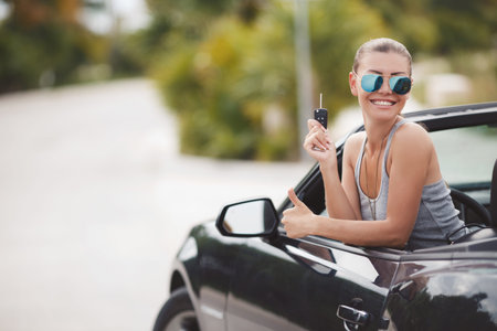 Beautiful young woman in a fancy black convertible.Girl driving a cool car. Cute fun lady, resting...