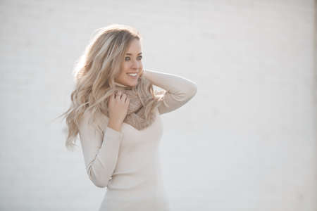 people emotions natural beauty and lifestyle concept, natural beauty and lifestyle concept-young beautiful woman in the city, street style spring summer beige scarf and white sweater.Closeup portrait of happy young woman smiling outdoorの写真素材