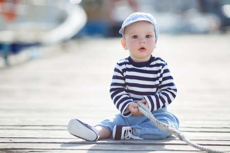 T-shirt, blue sneakers, blue sneakers and a pair of red jeans , a portrait against the background of boatsの写真素材