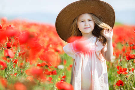 Happy cute girl in red poppies spring summerの写真素材