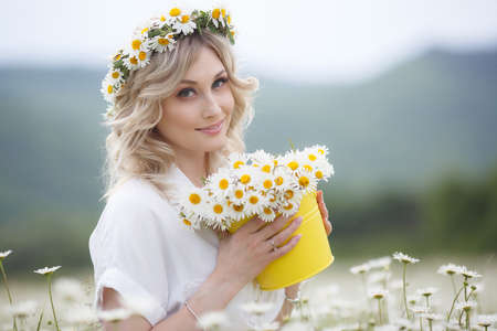 Beautiful girl enjoying the nature of white daisies, enjoying nature. Sun Light Field with Blooming Flowers, Sun Light. Young happy woman on spring meadow, countrysideの写真素材