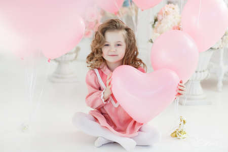 Fashion little girl model fece close up. Face female kid wiht happy emotion. Little girl hold heart, fathers, mothers day. Valentines day, love, birthday. Childhood, happiness, copy space Small girl child with a pink heart-shaped balloonの写真素材