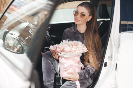 A girl holding a bouquet of flower is in the cars.