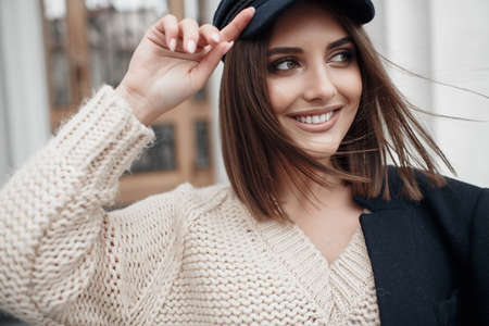 It is a woman who is wearing a pink sweater, black jacket and a capの写真素材