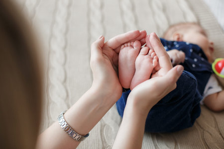 Young mother holding her newborn child. Woman and new born boy relax in a white bedroom. A young...