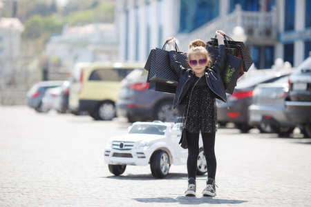 Fashion trend. Fashion shop. Little girl with bunch packages. Seasonal sale. Fashion girl customer. Happy child in shop with bags. Shopping day happiness. Birthday girl shopping. Fashion boutiqueの写真素材