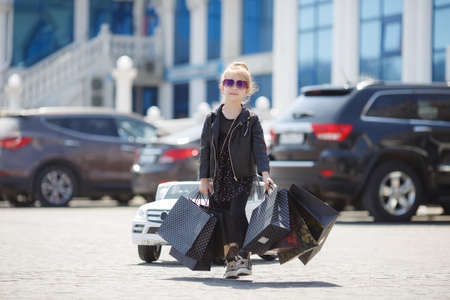 Fashion trend. Fashion shop. Little girl with bunch packages. Seasonal sale. Fashion girl customer. Happy child in shop with bags. Shopping day happiness. Birthday girl shopping. Fashion boutiqueの写真素材