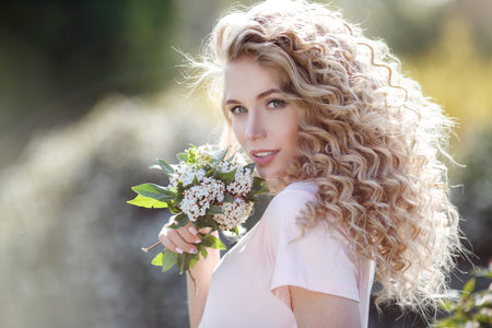 Beautiful young girl in a park. Woman in a blooming garden. Fashion, Cosmetics & Perfumes.Portrait...