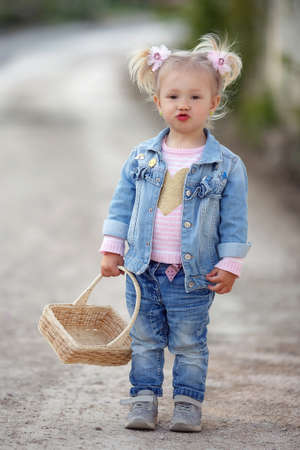 Little girl in the countryside on the country road in the countryside with a basket.の写真素材