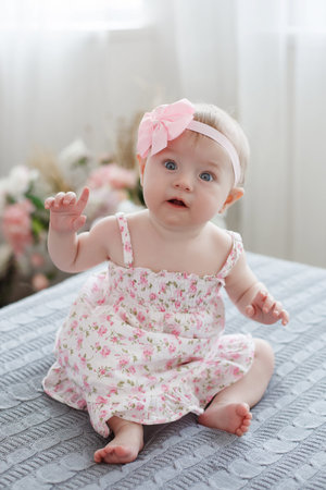 Adorable baby boy in white sunny bedroom plays alone on the bed.Charming Cute baby infant plays...