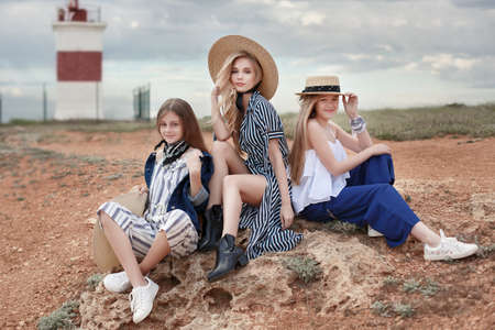 A group of young girls, teenagers on the rocky shore of the blue oceanの写真素材