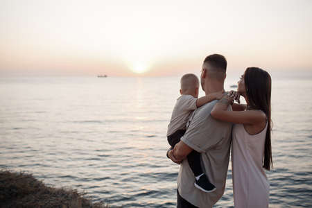 Young family with a child on a walk in the city in summer. Love and trust as family values. Mother and father with son outdoor. Summer vacation of happy family. Child with father and mother. Family with small kid on mothers or fathers day.の写真素材