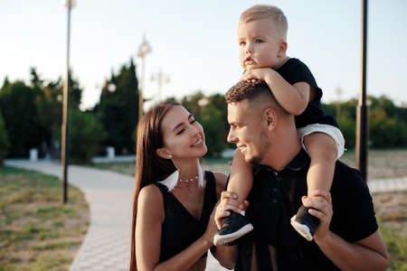 Young family with a child on a walk in the city in summer. Love and trust as family values. Mother and father with son outdoor. Summer vacation of happy family. Child with father and mother. Family with small kid on mothers or fathers day.の写真素材