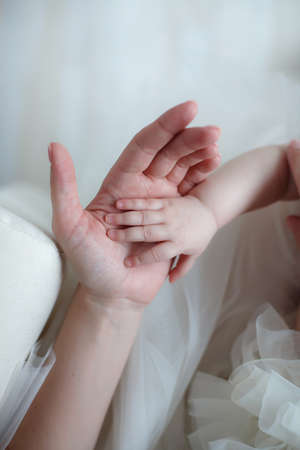 Palms newborn in the mother hands in soft focus. Small hands of a newborn baby in the tender palms of a caring mother. Mother holding her child's hand. Happy mom plays with a newborn baby.の写真素材
