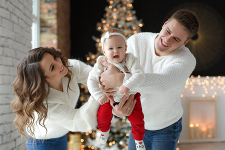 A happy family, father, mother and little daughter, spend time together on Christmas evening in a...